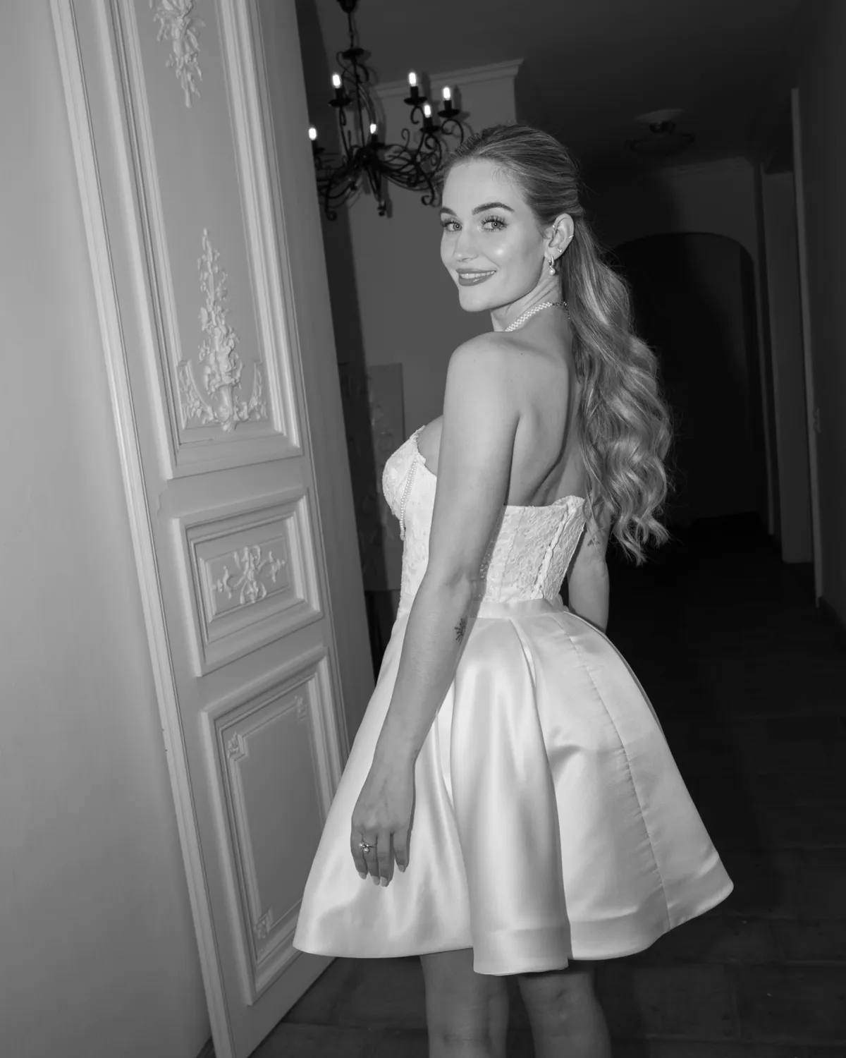 Braut im kurzen Brautkleid im Türrahmen, schwarz-weiß